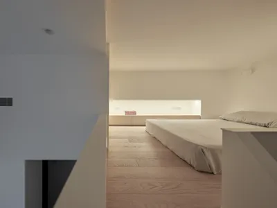 A minimalist bedroom featuring a wood floor and a bed with a minimalist design.