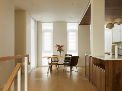 A modern kitchen featuring wooden cabinets, a dining table with chairs, and a wooden floor.