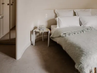 A minimalist bedroom with neutral-toned walls, fabrics, and soft lighting.