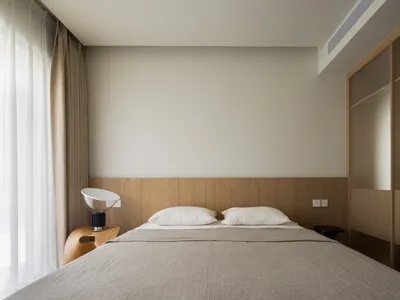 Modern minimalist bedroom with a bed, headboard, and minimalistic design elements.
