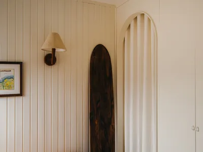 A minimalist bedroom featuring a wooden board and a bed with an orange blanket.