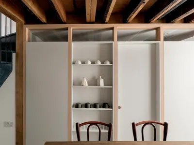 Modern kitchen featuring wooden shelves and minimalist chairs, designed for functionality and style.