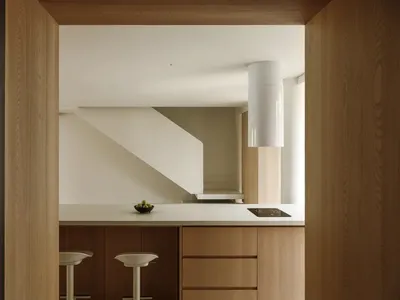 Modern minimalist kitchen with wooden cabinets and a white countertop.