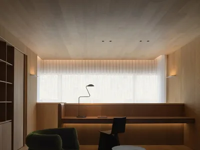 A minimalist living room with wooden elements and a concrete table, featuring a green armchair, a floor lamp, and a long tabl