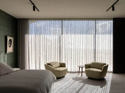Modern bedroom featuring fabric furniture and glass windows.