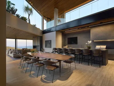 A modern lounge and kitchen featuring marble countertops and wooden dining table.