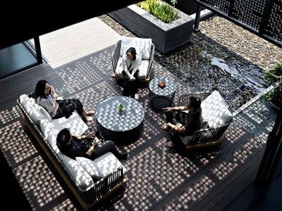 People sitting on white and grey cushioned lounge chairs in a modern patio setting.