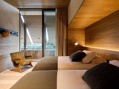A minimalist bedroom featuring wooden walls and a cozy bed setup.