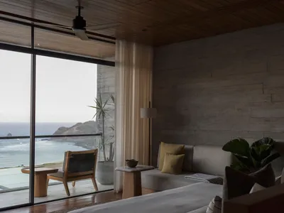 A minimalist bedroom featuring concrete, wood, and glass materials.
