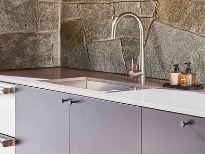A modern kitchen with a stone wall and stainless steel faucet