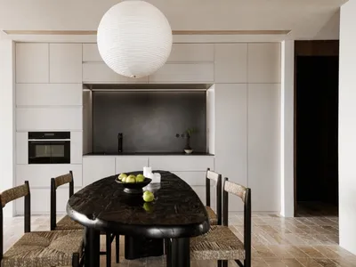 A modern minimalist kitchen with black table, white cabinets, and granite countertops.