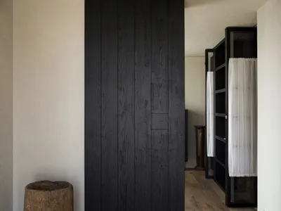 Modern minimalist bedroom featuring a black wood panel wall on a wooden floor.