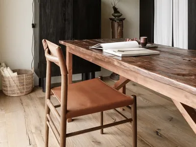 A modern home office featuring a wooden table and chair, minimalist decor, and natural lighting.