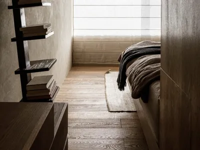 A minimalist bedroom with wooden floors and a bed.