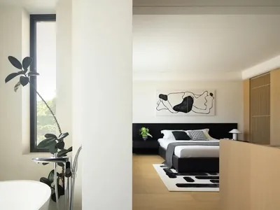 Minimalist bedroom featuring wood flooring and a concrete glass divider.