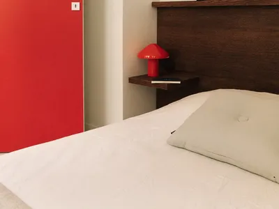 簡約臥室攝影，呈現紅色門、木質床頭板以及白色枕頭。