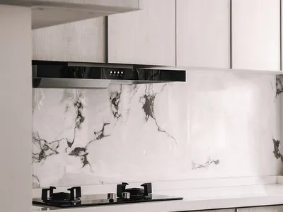 Modern kitchen with white marble backsplash and white wooden cabinets