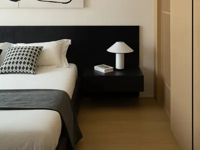 Modern minimalist bedroom featuring a black bed frame, white bedding, and a black and white abstract painting above the bed.