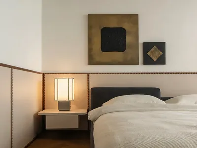 A minimalist bedroom with a bed, side table, and wall art.