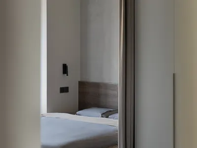 Modern minimalist bedroom with fabric bed and light walls and floor.