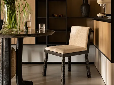 Modern kitchen with sleek wooden cabinets and metal accents, featuring a dining table and a tall vase with greenery.