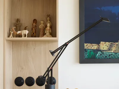 A minimalist bedroom with a modern desk lamp and wooden shelves.