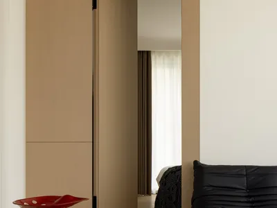 A minimalist bedroom featuring natural wood elements and a black leather sofa.