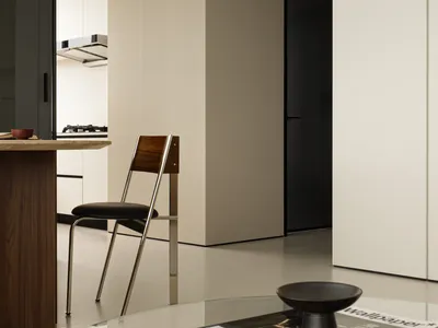 A modern minimalist living room with a concrete open-plan design, featuring a sleek wooden dining table and a black chair.