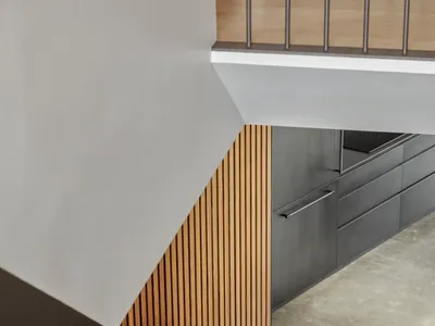 A modern kitchen with wooden paneling and dark concrete flooring.