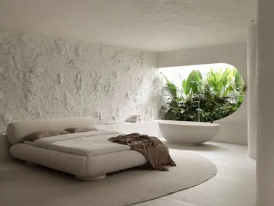 A minimalist bedroom featuring a concrete platform bed and bathtub in a circular room with greenery.