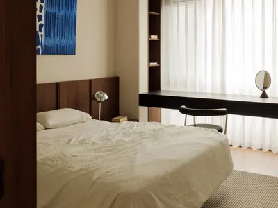 Modern minimalist bedroom featuring a bed with white bedding, curtains, and a glass window.