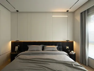 A modern bedroom with minimalist design, featuring a bed with grey bedding and black headboard, illuminated by a linear light