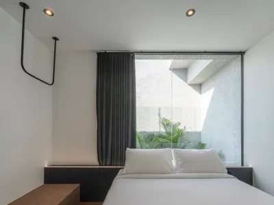 Minimalist bedroom with large glass window and concrete furniture.