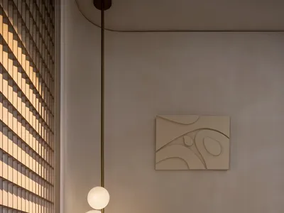 簡約臥室內有一張鋪著質感布料床罩的床，以及一盞懸掛式燈具。