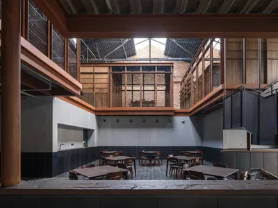 Industrial-style restaurant with concrete walls and floors, featuring concrete tables and chairs.