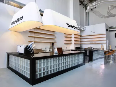 Industrial-style cafe with glass block counter, minimalist shelves, and pendant lighting.