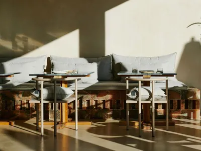 A modern cafe interior with wooden seating and marble tables and countertops.