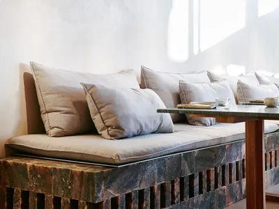 A modern living room with concrete seating area and light-colored cushions.