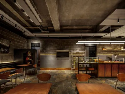 Industrial-themed restaurant interior with concrete walls, wooden tables, and metal elements.