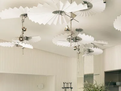 Modern restaurant interior with minimalist lighting, white ceiling fans, and green tiled floor.