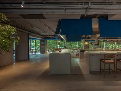 A modern restaurant kitchen with tile flooring and blue pendant lights hanging above a kitchen island.