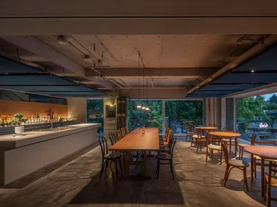現代餐廳室內空間，搭配木質餐桌、混凝土地板及玻璃元素。
