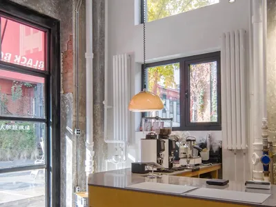 Interior view of a coffee shop featuring a wooden counter bar, high stools, and a modern coffee machine.