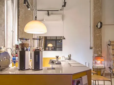Interior of a coffee shop featuring a wooden counter with coffee grinders and seating area in the background.