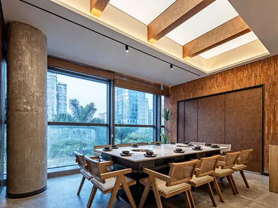 Industrial-themed restaurant interior featuring concrete walls, wooden chairs, and glass windows overlooking a cityscape.