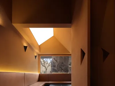 Leather booths in modern restaurant setting, illuminated by warm lighting from a skylight.