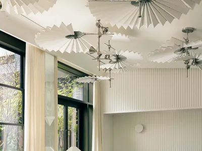 Modern restaurant interior with glass ceiling fans, wood tables, and metal bar counter.