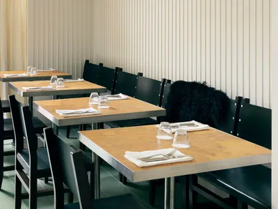 A modern restaurant interior with wooden tables and chairs.