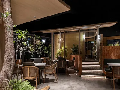 Modern restaurant interior with concrete flooring, wooden tables, and bamboo decor