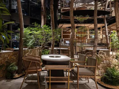 一間擁有茂密花園的現代餐廳，設有戶外座位與當代設計元素。